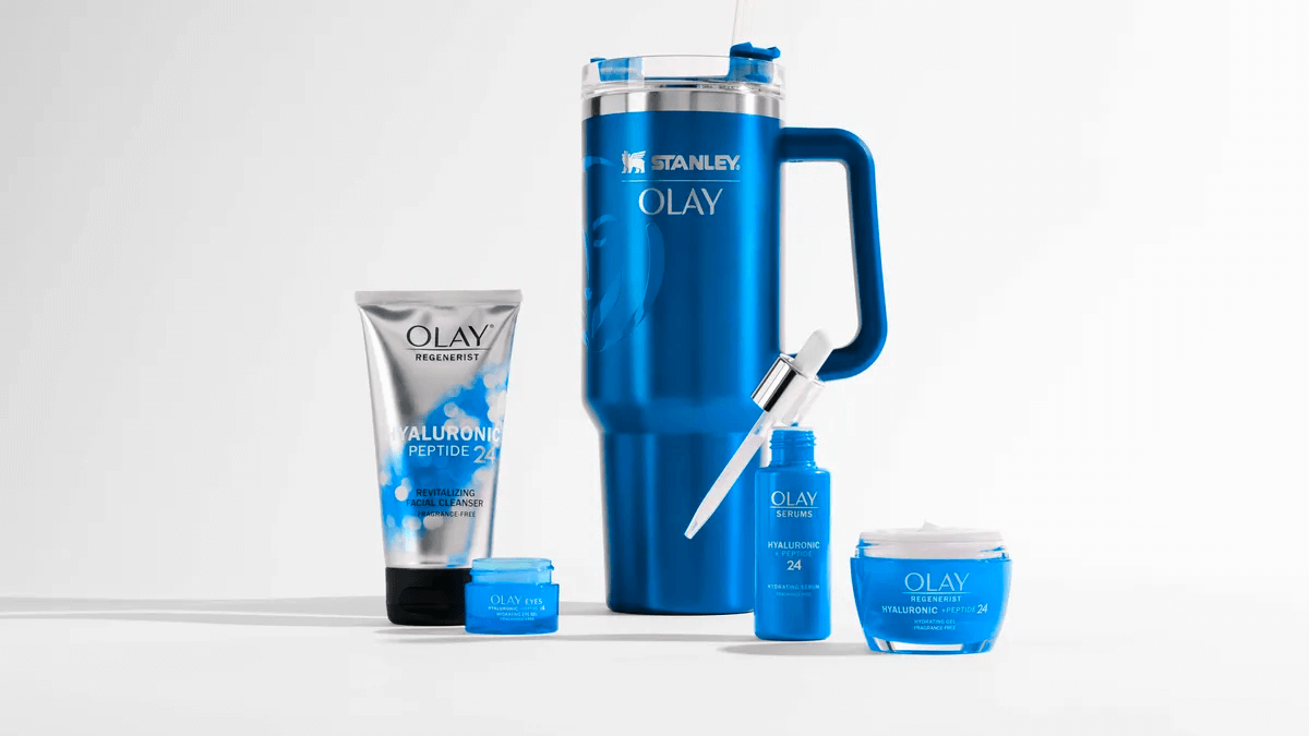 A product shot of the blue Stanley-Olay tumbler surrounded by Olay moisturisers and serums.