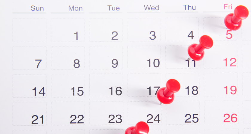 monthly calendar with push pins on several dates